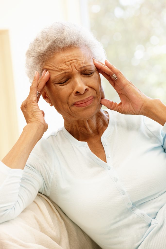 African American female distressed while massaging her temples. Falls in the elderly risk factors and preventions