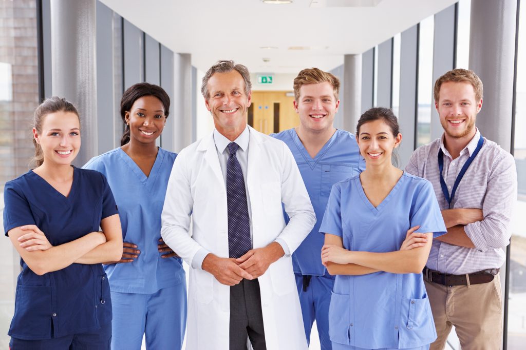 A group of doctors, nurses, physical therapist, occupational therapist, speech therapist smiling while standing in a hallway. Top 5 Benefits of Inpatient Rehabilitation