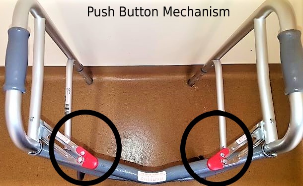 A top-view of an opened 2-wheeled rolling walker showing the push-button mechanism. 