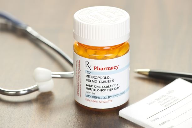 Image of medication bottle for Metroprolol sitting next to a stethoscope. Used to describe Prescription drug discount programs. 