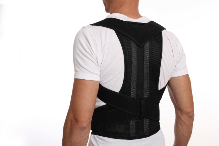 A picture of a man standing with a black back brace on (TLSO).