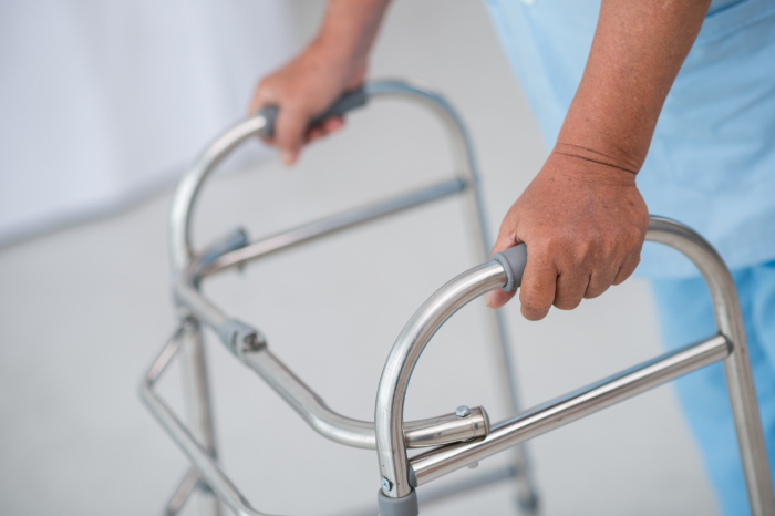 A picture of a man standing while holding a rolling walker.