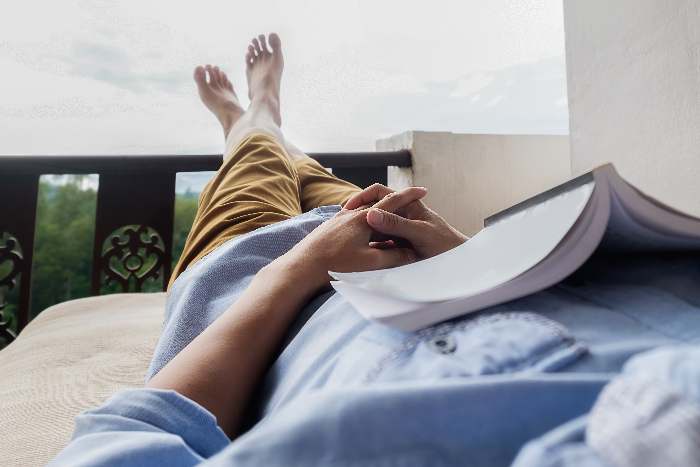 caucasian woman relaxing on patio while reading a book. stress-free